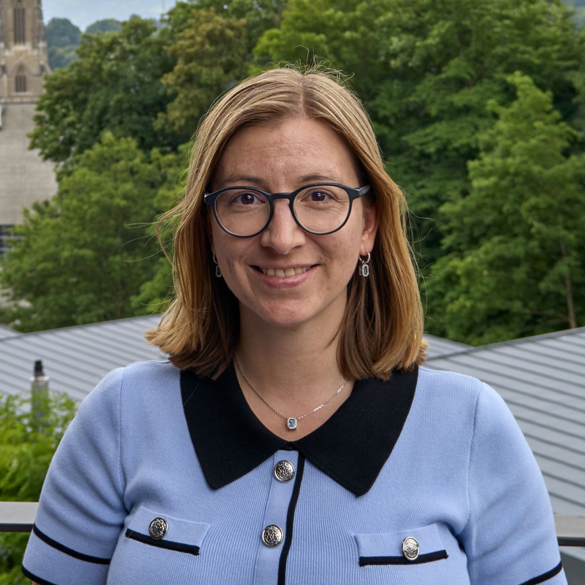 Porträtfoto von Gagnaux Rebecca. Sie trägt eine Brille und ein blaues Hemd.