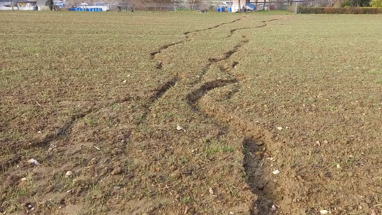 Ravines créées par ruissellement d‘eau sur un sol dénudé en pente, entraînant la terre vers un jardin familial.