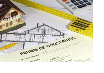 La maquette d'une maison, un dessin d'architecte, une calculatrice et un mètre ainsi qu'un document "Permis de construire"