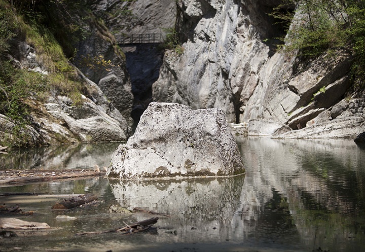 Agrandir l'image Un rocher dans l'eau avec un petit pont au deuxième plan