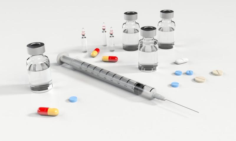 Une seringue, des fioles et des médicaments de diverses couleurs