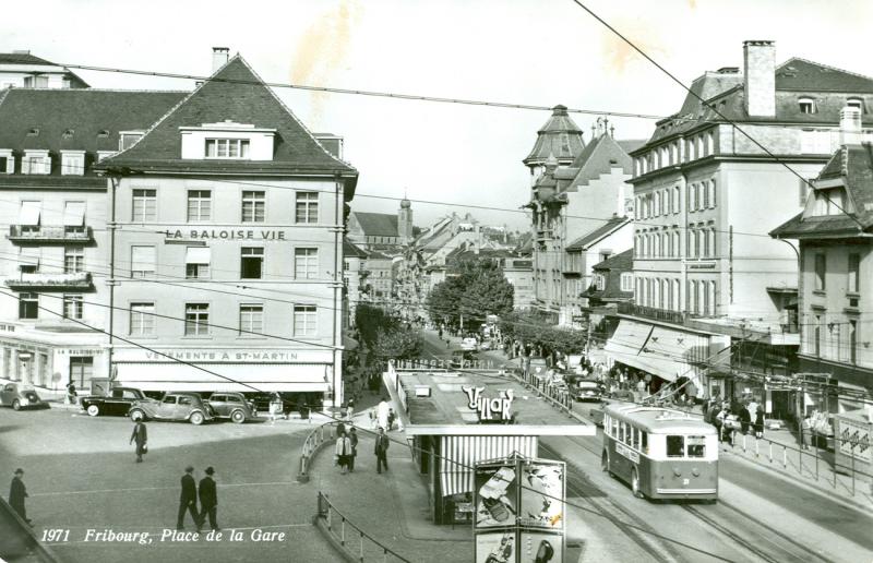 Au croisement des époques, la place de la Gare à Fribourg au temps des trolleybus Saurer (1964-1965), du kiosque de l'hôtel Terminus et de l'Epa-Unip, juste avant la tour de la Bâloise (1964-1965)