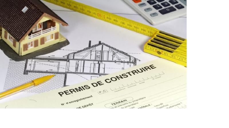 La maquette d'une maison, un dessin d'architecte, une calculatrice et un mètre ainsi qu'un document "Permis de construire"