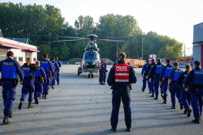 Polizeiaspirantinnen und -aspiranten marschieren in einer Reihe zu einem Helikopter