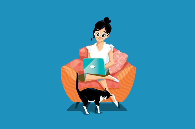 Une femme utilise un ordinateur portable assise sur un sofa orange, un chat à ses pieds