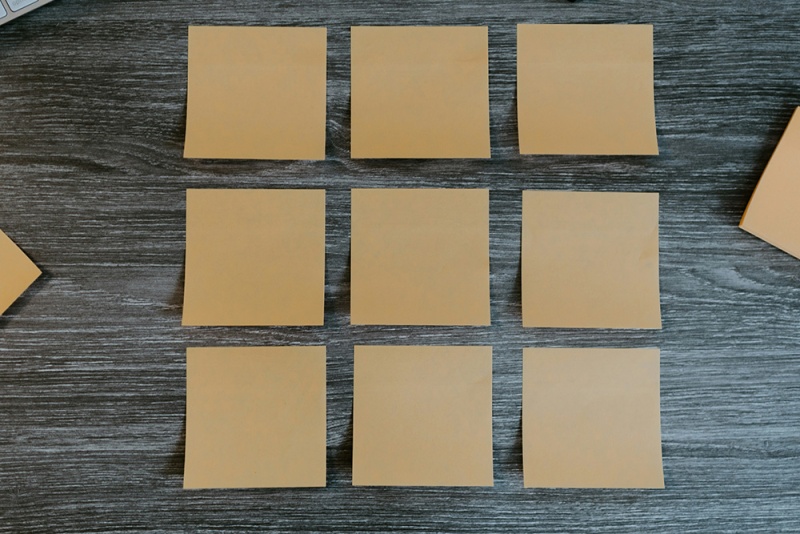Des post-it arrangés en carré sur un bureau en bois